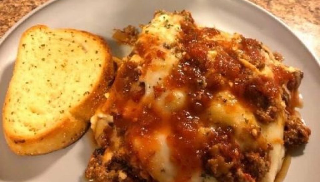 Plate of lasagna made with Dat Sauce with garlic bread.