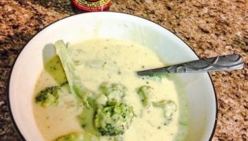 Bowl of Broccoli and Cheese soup with a bottle of Dat Sauce