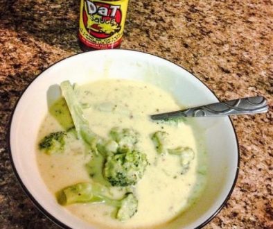 Bowl of Broccoli and Cheese soup with a bottle of Dat Sauce