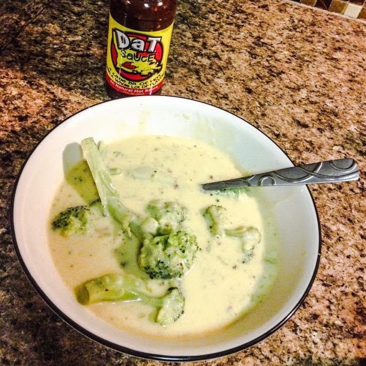 Bowl of Broccoli and Cheese soup with a bottle of Dat Sauce